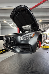 Mercedes-AMG GTC in matte black on lift during tire and brake service at Competition Car Care Florida.